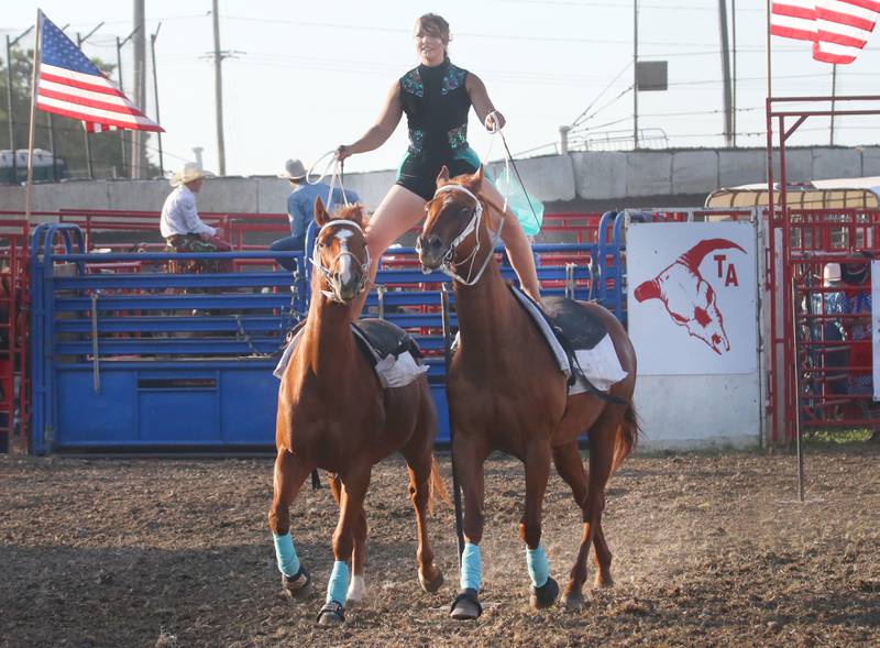 Saige McNeil of Grand Ridge, stands barefoot on top of two horses while straddling a pole during the Starved Rock Rodeo on Saturday, June 21, 2025 at the La Salle Speedway.