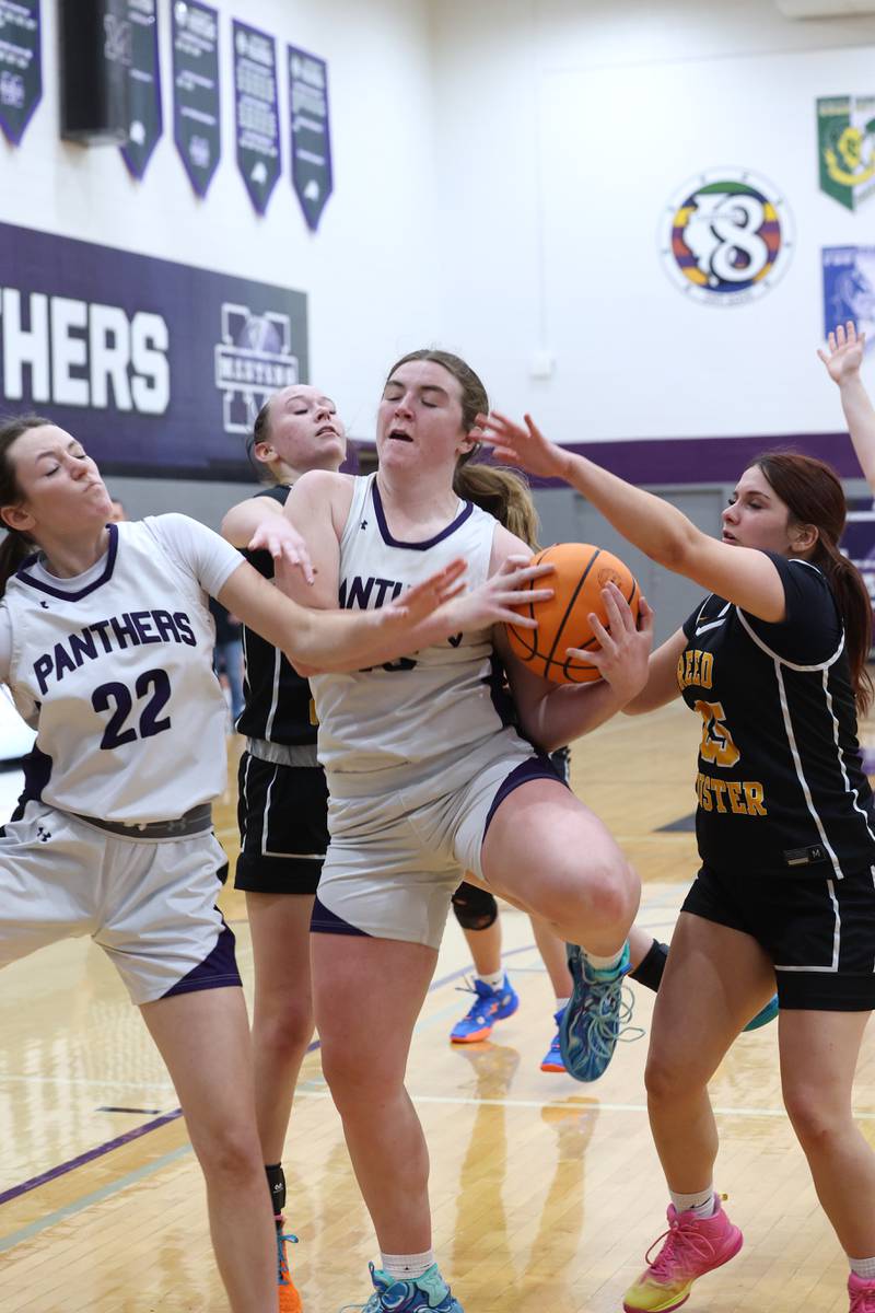 Manteno's Emily Horath, center, secures a rebound against Reed-Custer players during Reed-Custer's 45-42 victory over Manteno on Monday, Feb. 2, 2026.