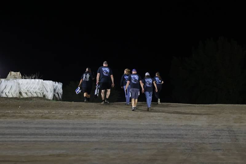 Members of the McCarty family cross the track to return to the pit after the final night of racing on Friday, Sept. 26, 2025, at the Kankakee County Speedway. Austin McCarty won the Pro Late Model title for the second year in a row, earning the McCarty family's 10th overall title following a bittersweet racing season.