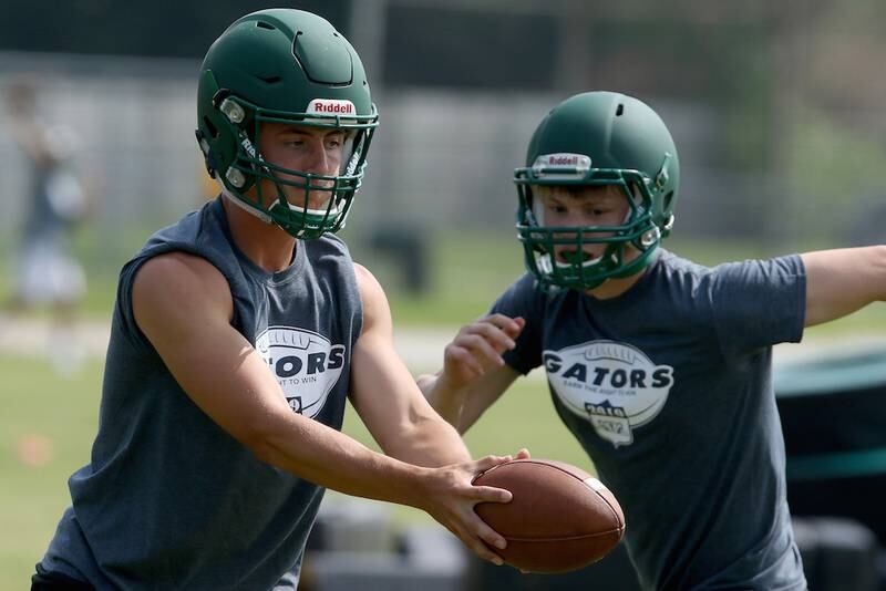 Crystal Lake South quarterback Ian Gorken, left, looks for the handoff during football practice at Crystal Lake South High School on Monday, July 8, 2019 in Crystal Lake.