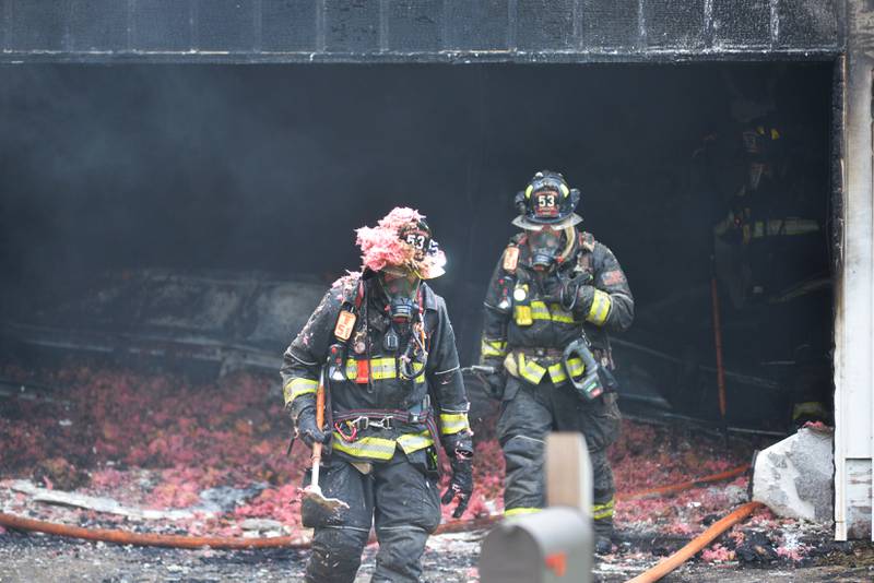 Oregon firefighters exit a charred garage while battling a fire at 540 E. Elizabeth Road, southeast of Oregon, on Wednesday, Aug. 20, 2025.