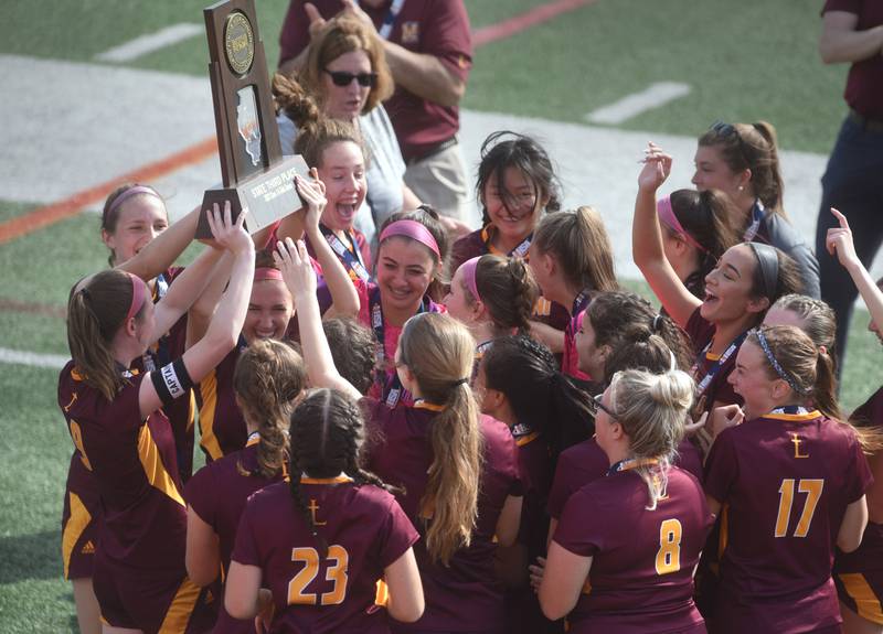 Paul Valade/pvalade@dailyherald.com
Montini players gather around the third-place trophy after defeating Normal University during Saturday’s IHSA Class 1A state girls soccer consolation game at North Central College in Naperville