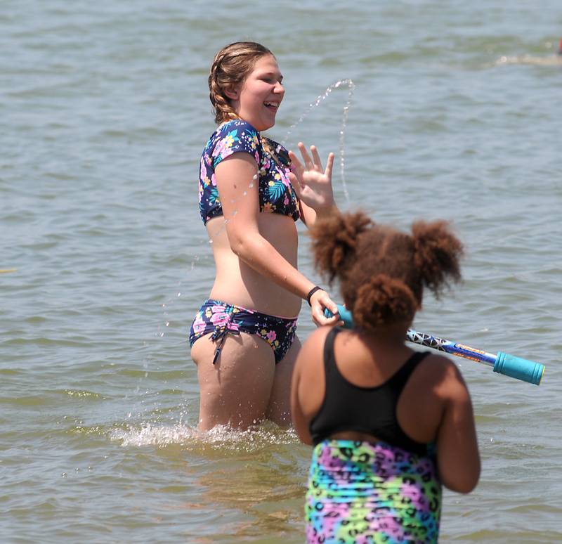 Adyson Staruck tries to avoid being squirted by Tessa Amos, 7, as they play Tuesday, June 14, 2022, in the cool waters of McCullom Lake while at Petersen Park Beach, as temperatures in the McHenry County area reached the mid-90’s.