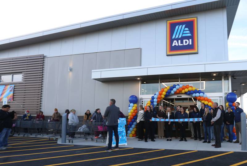 Aldi employees gather during the ribbon-cutting of the new store on Thursday, Nov. 13, 2025 at the corner of Backbone Road and North Main Street  in Princeton. The 12,000 square feet store began construction in May of this year. The first 100 people in line were given a chance to win a golden ticket to win a $100 gift card. Hundreds of people waited in line for free gift bags. The store hours are 9a.m.-8p.m. daily.