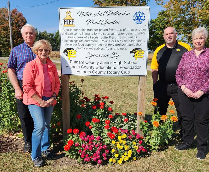 Reed Wilson, garden co-developer and president of the Putnam County Educational Foundation;  Sandy Miller, garden co-developer and University of Illinois Master Naturalist; Cheri Adrian, president of the Putnam County Rotary Club; Mike Olson, principal of Putnam County Junior High School and PC Rotary vice president pose in front of a pollinator garden at the junior high school. Absent from photograph is Mark Wackerlin, Putnam County Junior High School custodian and garden curator.