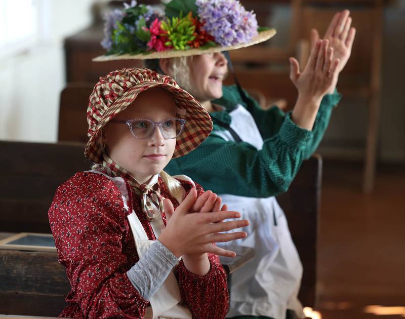 Southeast Elementary School third graders Brynlee Monney (front) and Cece Zantout applaud another students correct answer Tuesday, Nov. 4, 2025, during a field trip to North Grove School, a one-room schoolhouse from 1878 in Sycamore.
