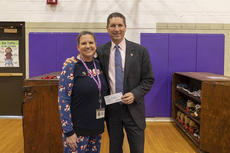 Brett Nicklaus of Trinity Cares, donates a check to Jefferson School principal Crystal Thorpe Friday, Dec. 20, 2024. The money pays off the lunch debt for some students at the school.