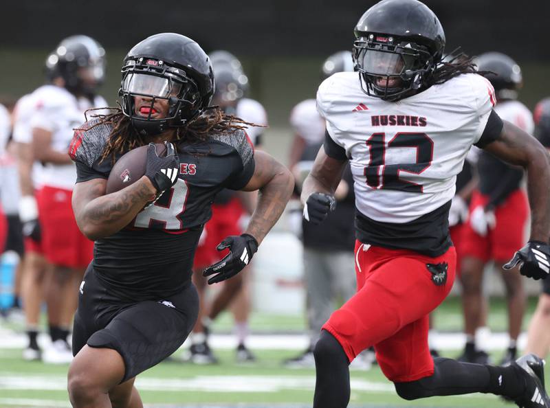 Northern Illinois University running back 	Triston White carries the ball towards the end zone with defensive back Aaron Warren in pursuit Tuesday, April 14, 2026, during spring practice in Huskie Stadium at NIU in DeKalb.