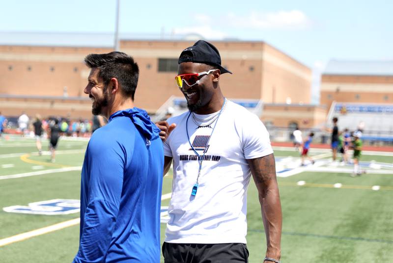 Former St. Charles North standout and current New York Giants defensive back Tyler Nubin shares a laugh with St. Charles North Head Coach Rob Pomazak on the first day of a three-day football camp on Friday, June 20, 2025 in St. Charles.