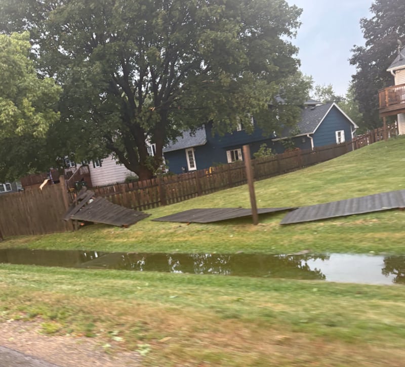 A fence is broken and water stands along Cary Algonquin Road in Cary after storms caused widespread damage in the area on Aug. 16, 2025.