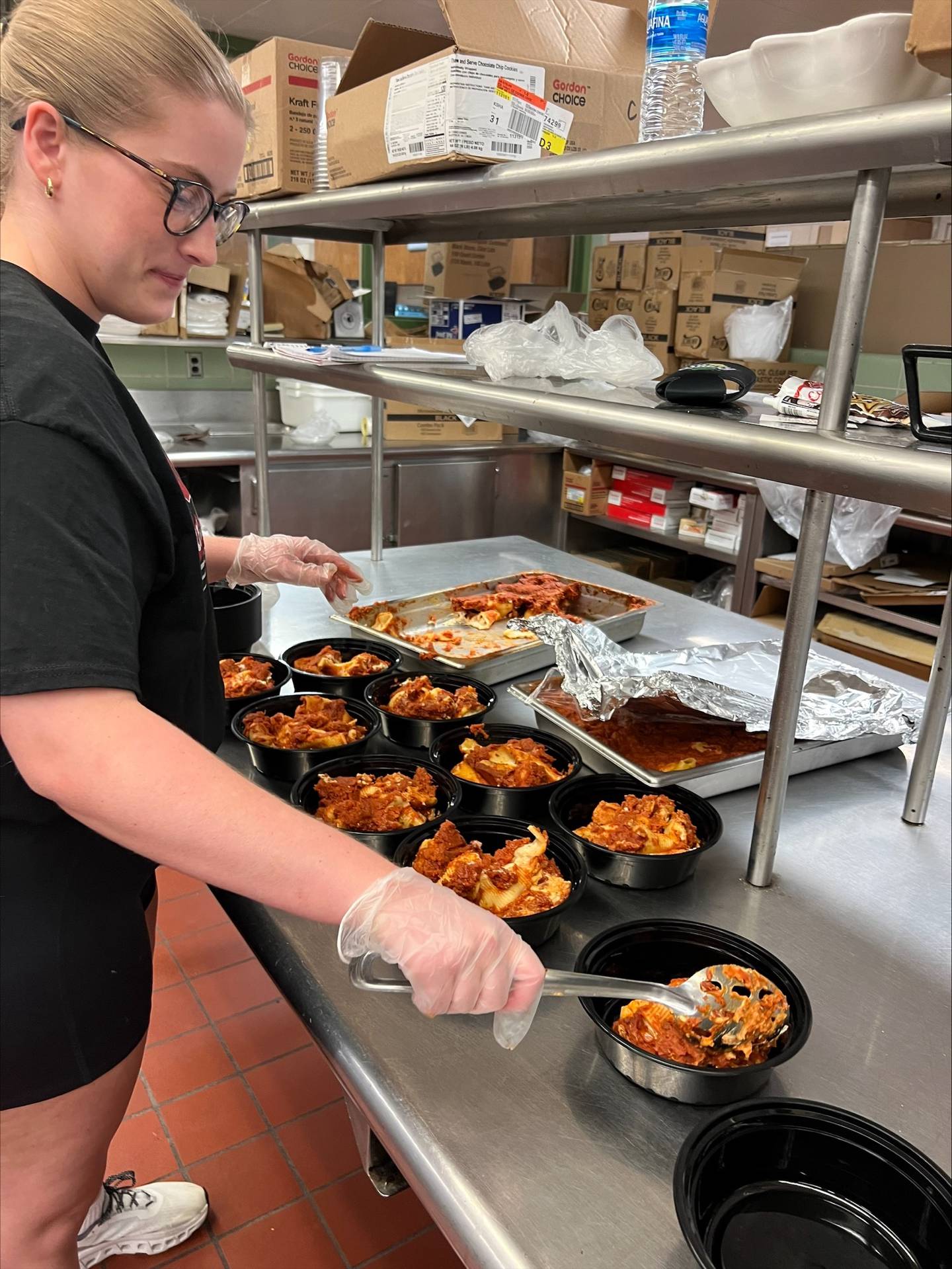 A student packages leftover food into ready-to-go frozen meals for students to enjoy for free through Northern Illinois University Huskie Harvest program. The initiative aims to reduce food waste and address food insecurity.