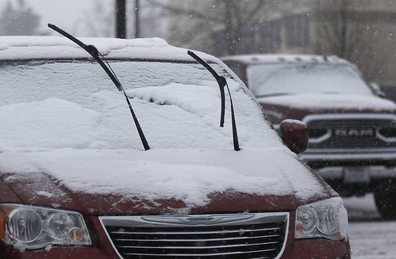 Windshield wipers are raised to make it easier to remove snow and ice from a vehicle in the parking lot of McHenry County Government Center in Woodstock, as a winter storm moves through McHenry County on Tuesday, Jan. 9, 2024, delivering snow to most of the county.