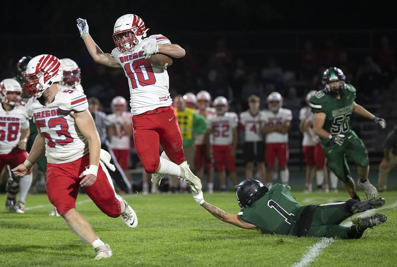 Oregon’s Keaton Salsbury leaps over a Rock Falls tackler Friday, October 11, 2024, in Rock Falls.