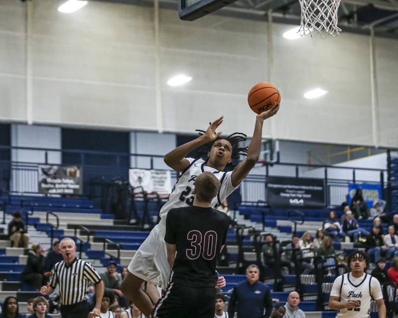 Oswego East's Mason Lockett IV (23) draws a blocking foul from Plainfield North's Carson Miller (30) during their basketball game between Plainfield North at Oswego East Friday, Dec 5, 2025 in Oswego.