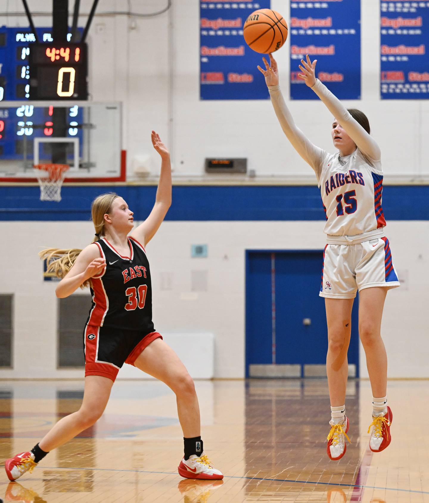 Glenbard South's Jordan Bailey, right, hits a three pointer as Glenbard East's Kathleen Nevels tries to defend the shot during Friday’s game in Glen Ellyn.