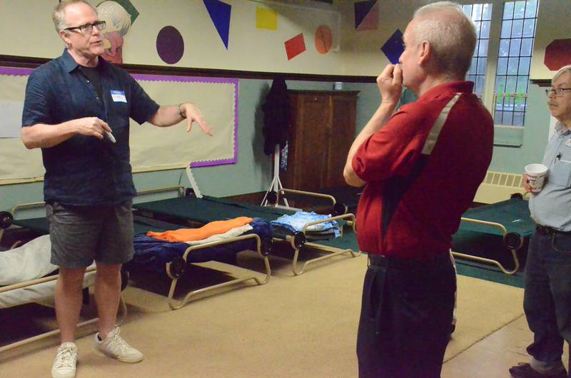 Thew Elliott (left) warming center volunteer at Wesley United Methodist Church in Aurora, conducts a May 2025 tour of the center. New and used backpacks are sought for center patrons.