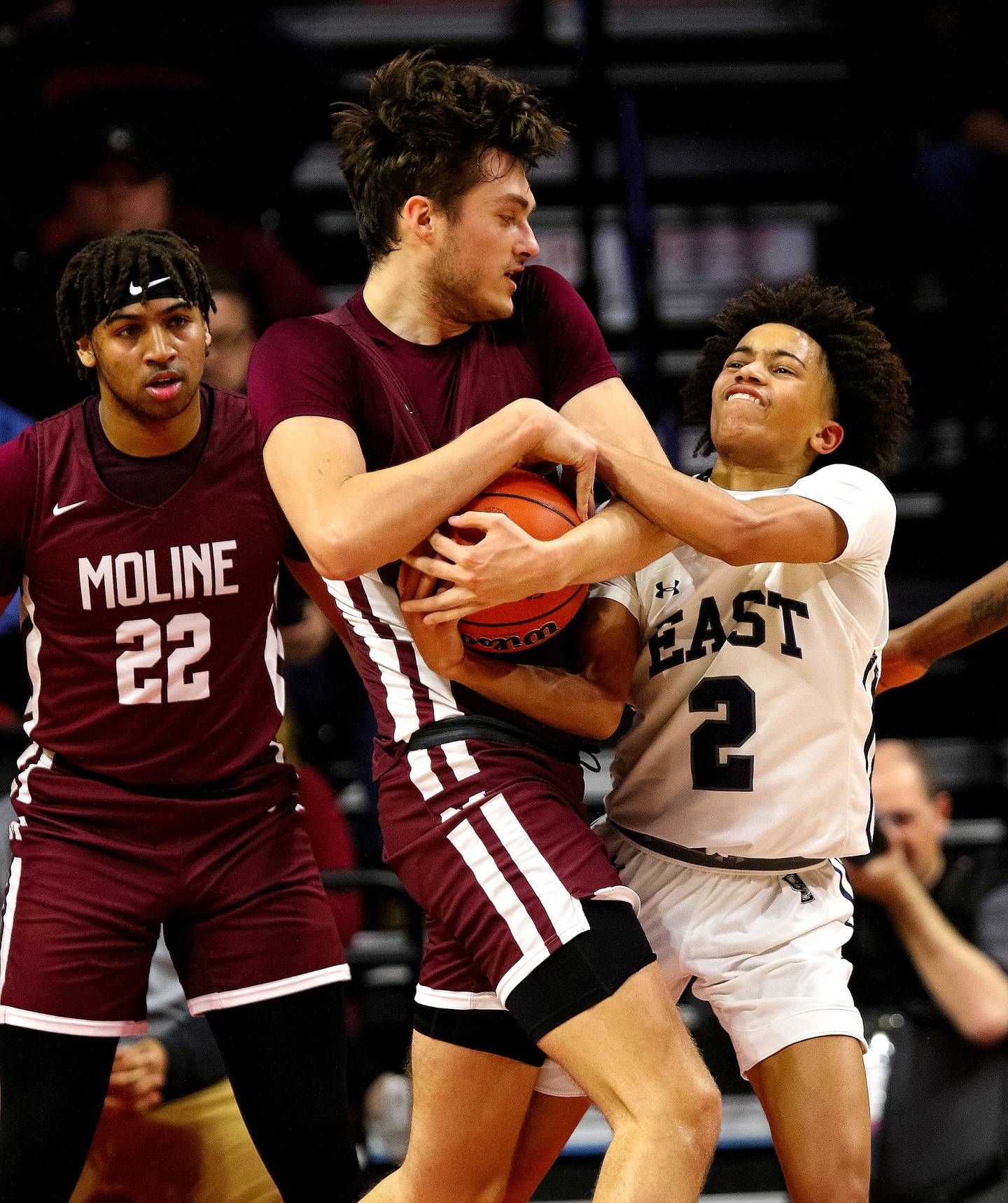 While Trey Taylor looks on from the paint, Oswego East's Bryce Shoto fights for a rebound with Moline's Owen Freeman (left) during first half action in his team's supersectional game against Moline. The Wolves fell 59-55 to the Maroons ending this season Class 4A postseason run.    (Photo: PhotoNews Media/Clark Brooks)