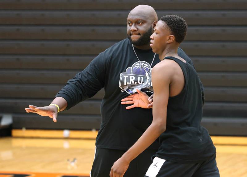 Jay Moore, founder of TRUTH Basketball Academy and an assistant basketball coach at DeKalb High School, plays defense against Gabe Crump, 15, from DeKalb, during a drill Tuesday, June 25, 2024, during a session at the school.