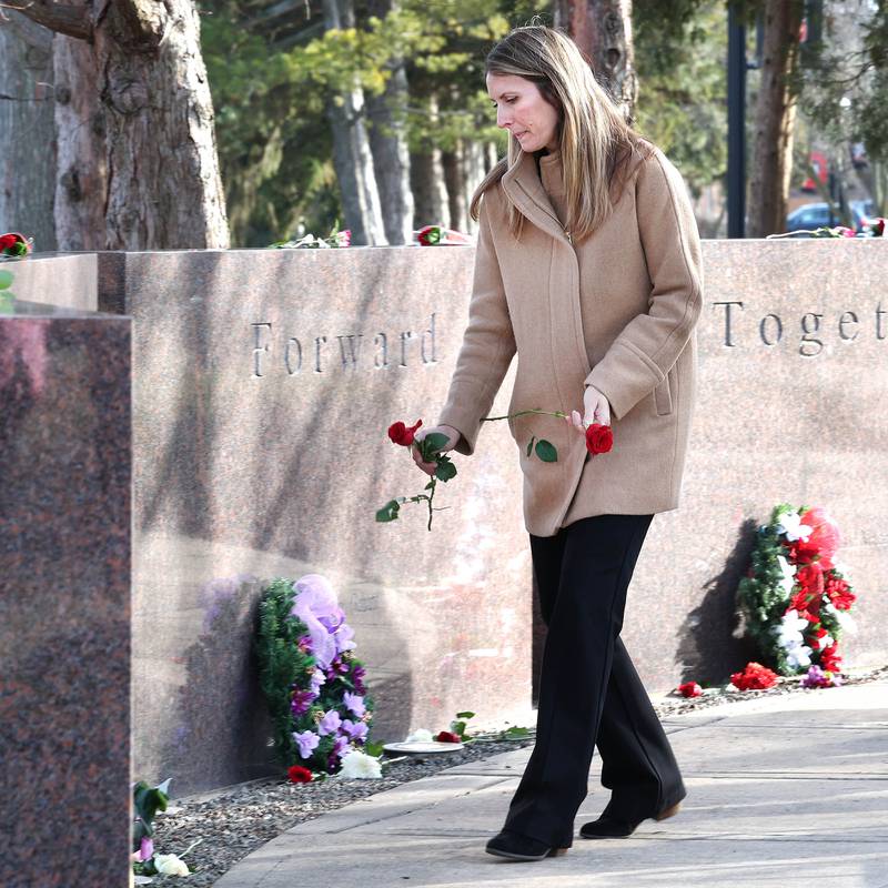 Amy Ogden puts flowers at the base of each stone Wednesday, Feb. 14, 2024, during a ceremony in the Peaceful Reflection Garden near Cole Hall at Northern Illinois University honoring the victims of the 2008 shooting on campus in DeKalb. Wednesday marked 16 years since the deadly shooting took place at NIU which took the lives of five people.