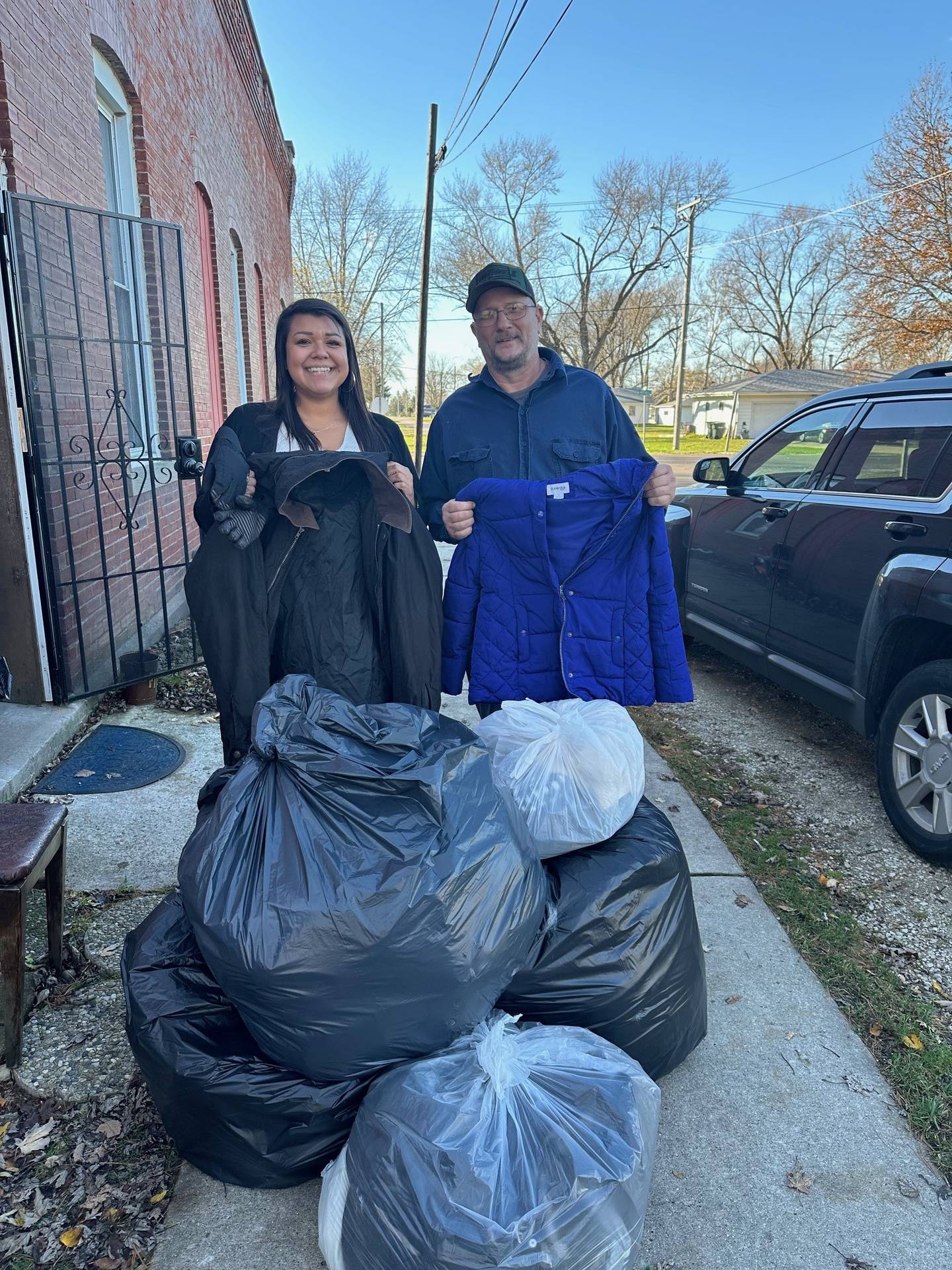 A representative from The Forgotten Garden in Braceville (right) accepts the coat donation from Grundy Bank's Christine Mendez.