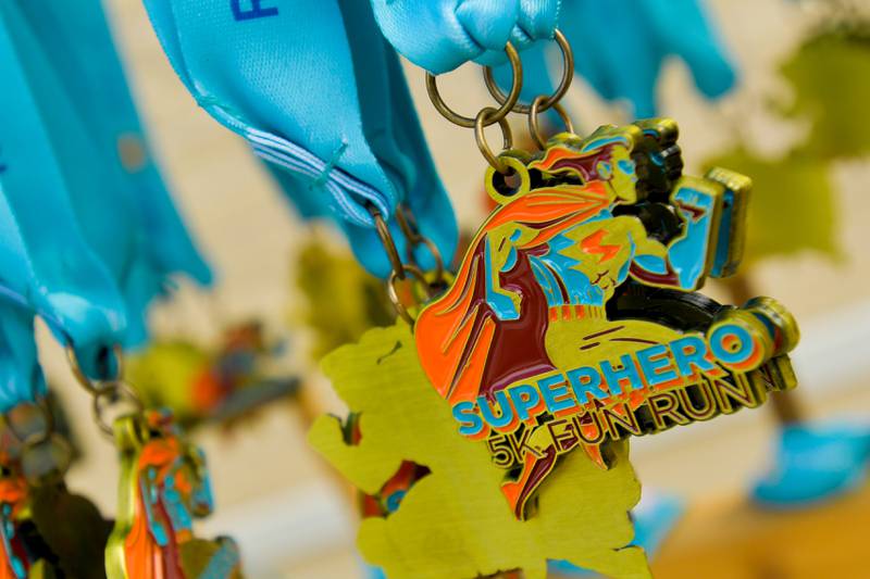 Super Hero 5k Fun Run medals await pickup from runners in Wheaton on Saturday, April 15, 2023.