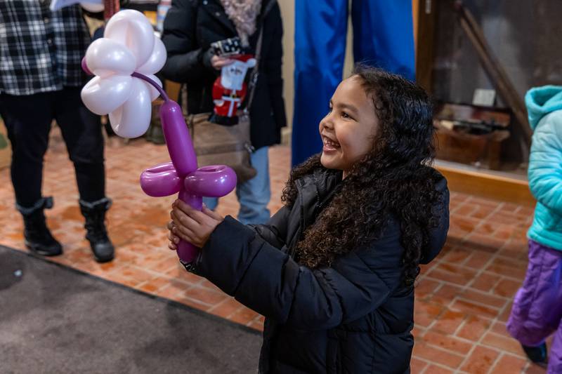 Lockport resident Aubrey Jones shows off a flower balloon she received inside Lockport City Hall during Lockport’s Christmas in the Square festivities on Nov. 29, 2025.