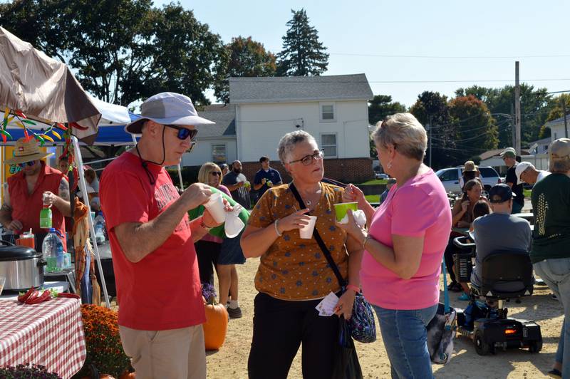 Susan Cavanaugh, right, of Polo, talks to Laura and Jim Vock, of Bloomington, during Polo's Chili Cook-Off on Sept. 30, 2023. The cook-off was held in the city-owned lot next to the Shell station; it was the first time the event has taken place since 2019.