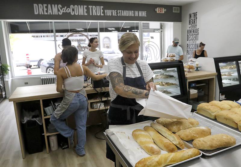 Rachel Skubiszewski puts a loaf of French bread into a bag as she waits on a customer on Friday, June 27, 2025, at the recently opened Black Market Bakery in downtown Crystal Lake.