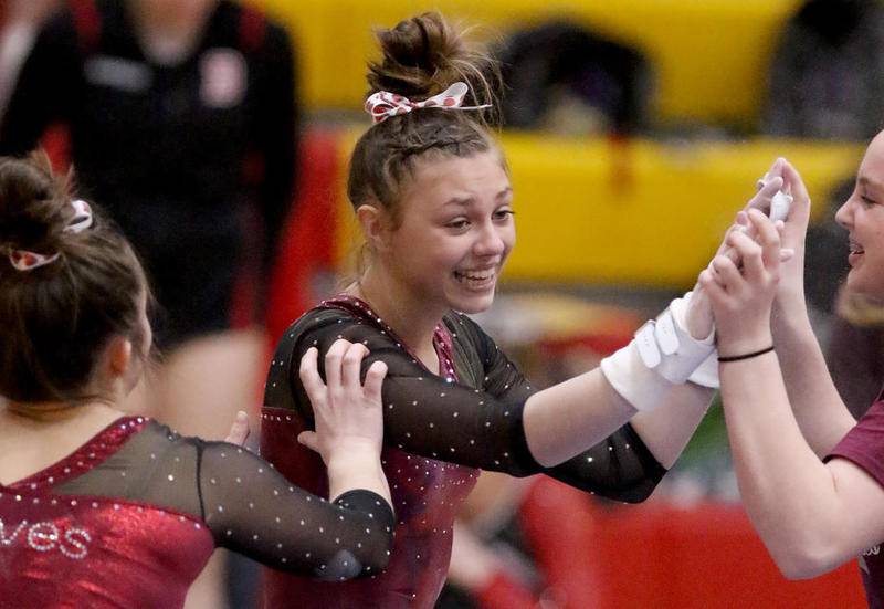Prairie Ridge co-op's Gabby Riley is congratulated by teammates after performing on the uneven bars during the Schaumburg Sectional on Wednesday in Schaumburg. The Wolves won the team championship.