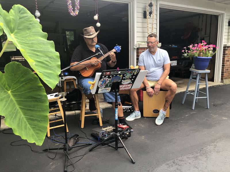 An elephant ear plant helped lend an tropical feel for George Klingelhofer, left, and John Biloz as they played island calypso music in the driveway during International Play Music on Your Porch Day, Saturday, Aug. 26, 2023, in Wonder Lake.