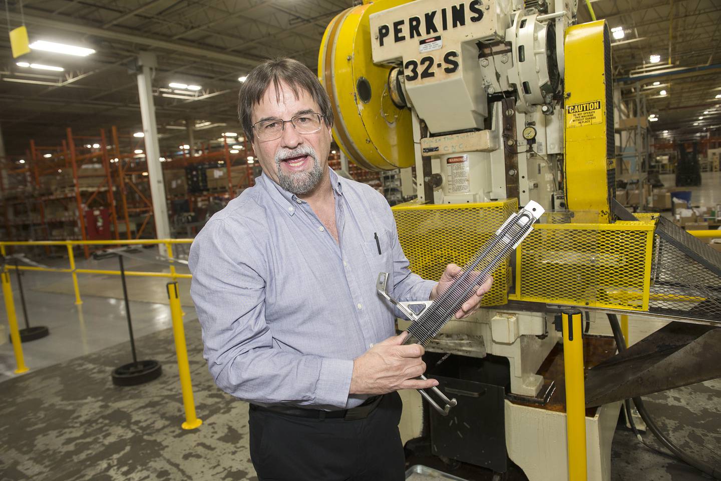 Plus and Edelmann general manager Dave Daniels stands in front of the machine that will punch out the fins for the cooling mechanism.