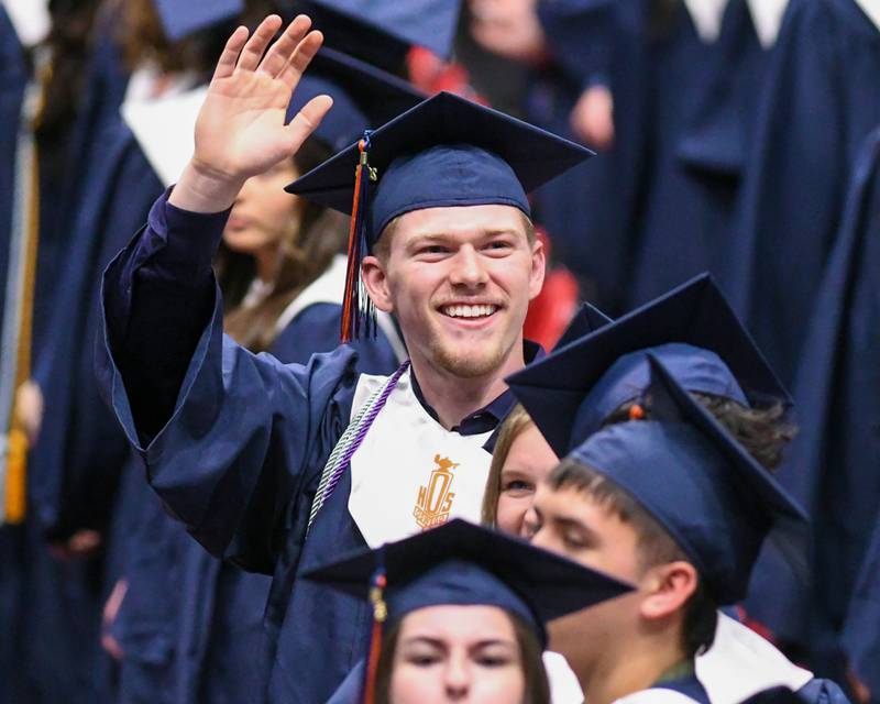 An Oswego High School graduate waves to audience members as he walks into the graduation ceremony on Saturday May 17, 2025, held at the Convocation Center in DeKalb.