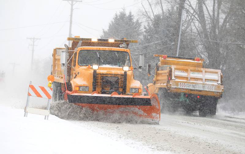 Plow trucks pass each other on Hart Road in Batavia during a snow storm.
