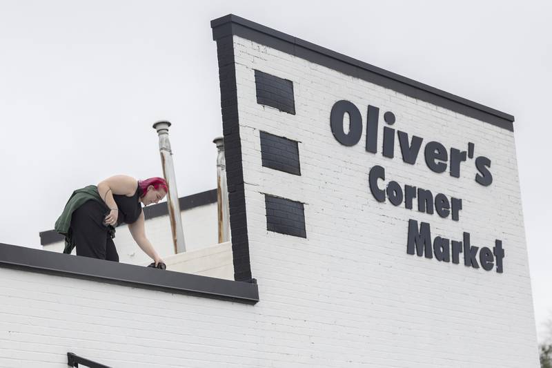 Photographer Falan Schwarz takes her perch on the top of Oliver’s Corner Market Saturday, April 4, 2026, for a group picture of family and employees of the closed grocery store.