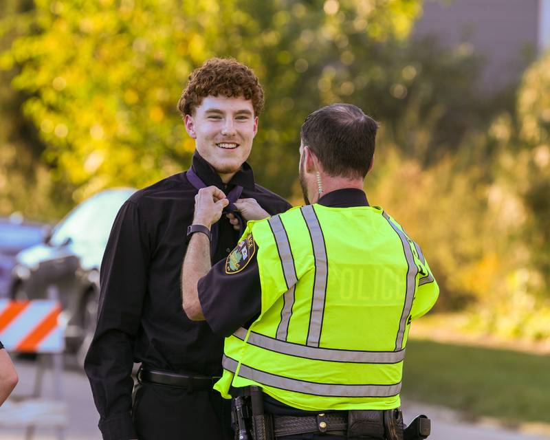 Sycamore High School senior Aidan Mesenbrink gets some help tying his tie courtesy of Sycamore Deputy Police Chief Ryan Hooper before the Spartan's Homecoming Parade on Wednesday, Oct. 8, 2025, downtown.