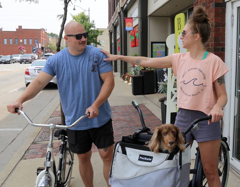 Terry Klosak, Amanda Roman and her dog Parker, take a bike ride as they explore Boo Boo Days sales in Batavia on Sunday, July 13, 2025.