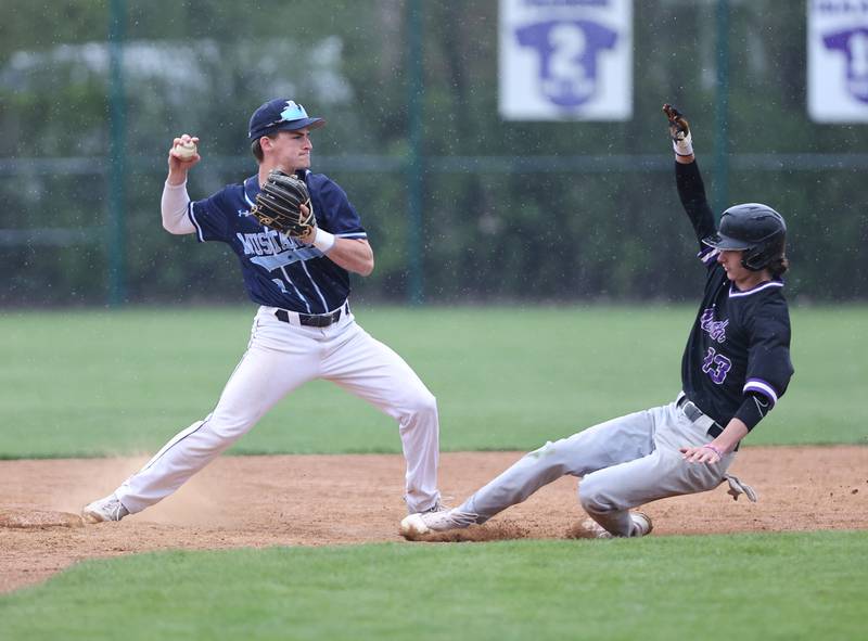 Downers Grove South's Aaron Davis (2) starts a double play as Downers Grove North's Jude Warwick (13) slides into second during the varsity baseball game between Downers Grove South and Downers Grove North in Downers Grove on Saturday, April 29, 2023.