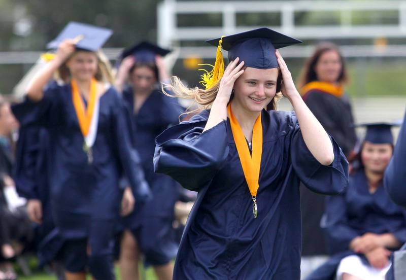 Sarah Lind holds her cap from the wind as she walks to receive her diploma during graduation at Cary-Grove High School in Cary on Saturday, May 17, 2025.