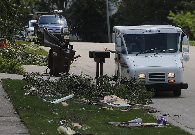 Mail is delivered as debris lines the road in the 10700 block of Timer Drive West in Huntley on Thursday, July 13, 2023, after a confirmed tornado took the roof off the building in Huntley on Wednesday.