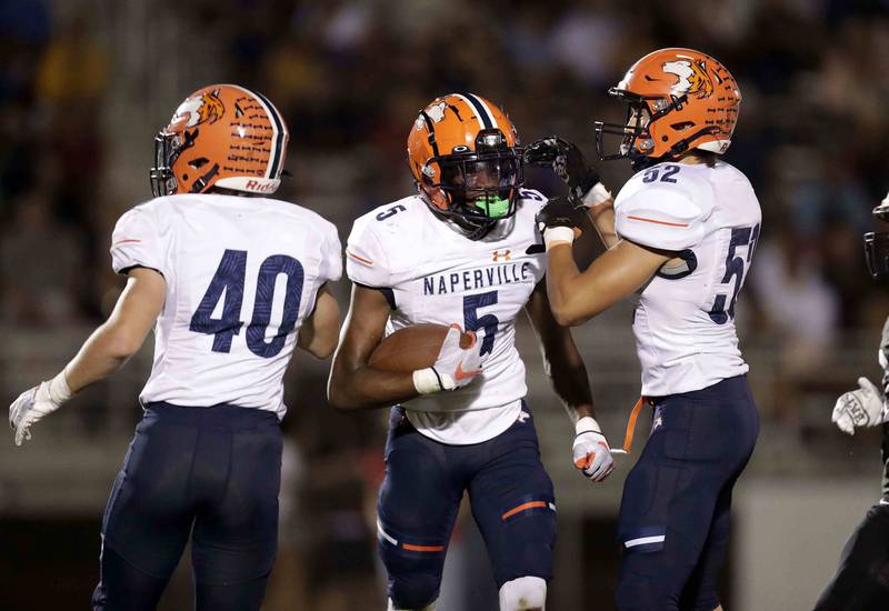 Naperville North's Luke Williams (5) celebrates his interception with teammates Luke Keough (40) and Ryan Anderson (52)  Friday September 16, 2022 at Barbara J. Barrows Stadium in Naperville.