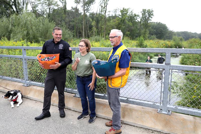 Marty Keller (right), past president of the Wheaton Lions Club, and Milton Township Supervisor John Monino (left) join Forest Preserve District of DuPage County Chief Partnership and Philanthropy Officer Jeannine Kannegiesser (center) before dropping over 200 rubber ducks into a restored stretch of Spring Brook at St. James Farm Forest Preserve in Warrenville on Thursday, Sept. 7, 2023 during the Friends of the Forest Preserve District of DuPage County’s rubber duck race fundraiser.