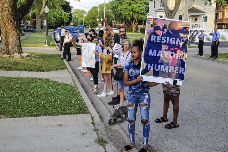 A dozen demonstrators can be seen chanting and waving signs Friday outside Mayor Bob O'Dekirk's home along Buell Avenue in Joliet.