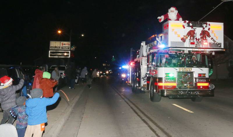 Santa Claus waves to children during the annual Christmas Parade on Saturday, Dec. 7, 2024 on Peoria Street in Peru.