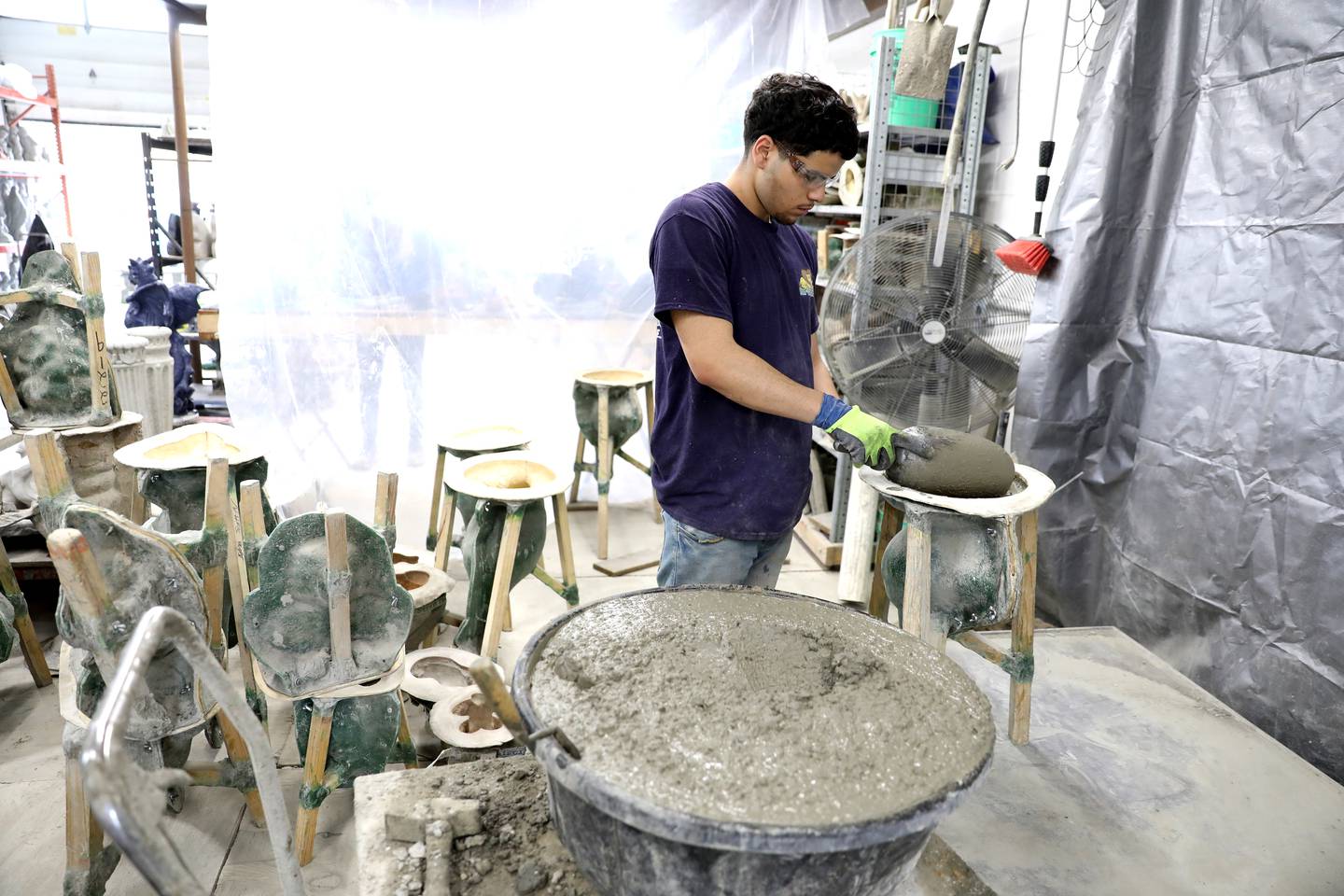 Jay Gonzalez paints pours concrete into molds at Lion Concrete in Oswego. The shop, which was founded in 1925, is celebrating its 100th anniversary this year. The company, owned by Oswego couple Valerie and Scott Neupert, is now in its third generation.