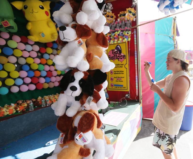 Charles Medrow, of Ottawa, throws a dart at a balloon Wednesday, June 15, 2022, during the Lions Club Carnival in downtown Ottawa. The carnival features food, rides, and games and runs through Saturday, June 18.