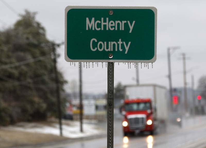 A semitruck travel east on Route 173 as ice hangs on a McHenry County sign Wednesday, Feb. 22, 2023, as a winter storm that produced rain, sleet, freezing rain, and ice moved through McHenry County.