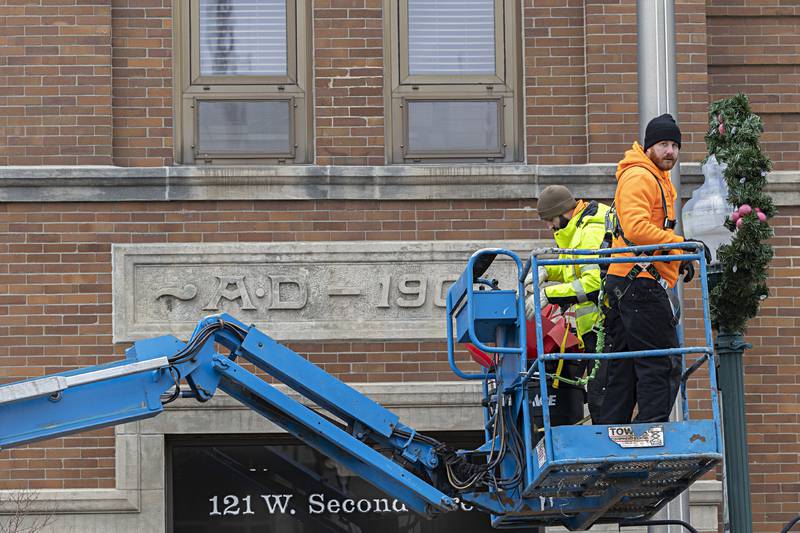 Dixon street department’s Steve Fassler (left) and Austin Clark work to remove the holiday decorations Wednesday, Jan. 3, 2024 from the downtown. Crews worked to dismantle the decorations ahead of potential snow next week.