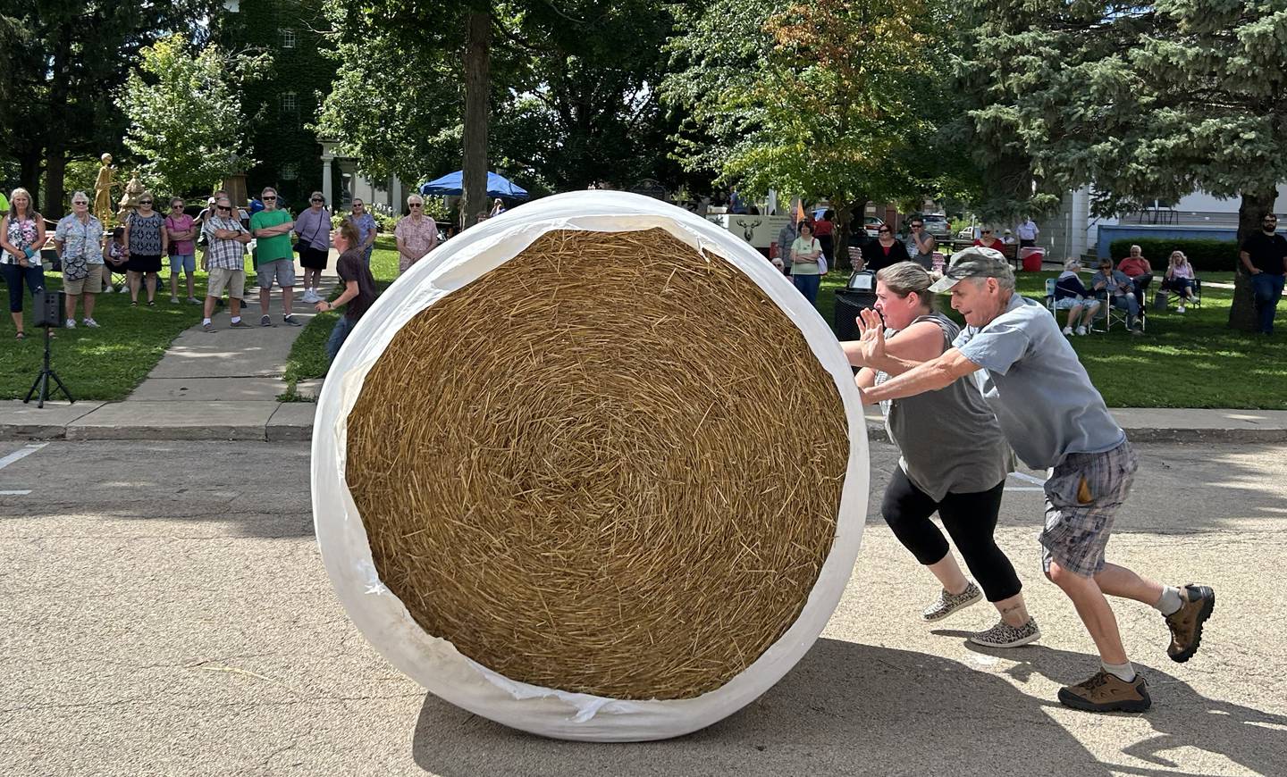 Tiffany West and Tom Steuerwald of Mt. Morris roll a large round straw bale down Wesley Avenue in Mt. Morris during the Straw Bale Race at Strawfest on Saturday, Aug. 23, 2025. The team with the fastest time won the event. This team's time was 11.90 seconds.