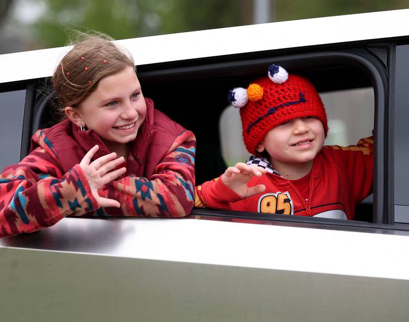 Carolynn Morong (left) and her brother Marshall Morong wave from a Tesla Cybertruck to a crowd waiting to welcome Marshall to Hinckley-Big Rock Elementary School Monday, May 5, 2025. Marshall returned to school months after receiving a heart transplant.