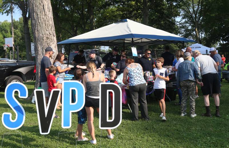 People gather around the Spring Valley Police tent during the National Night Out event on Tuesday, Aug. 5, 2025 at Kirby Park in Spring Valley. The event featured prizes, dodge ball tournament, bounce house, face painting and more. National Night Out is an annual community policing campaign held on the first Tuesday of August to create police-community partnerships and build safer neighborhoods.